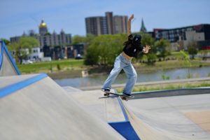 woman skateboarding at Lauridsen Skatepark, with Des Moines capitol in the background